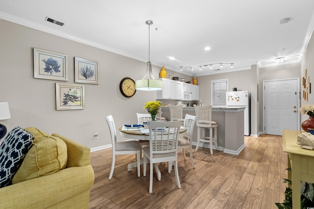 dining space with ornamental molding and light hardwood / wood-style floors