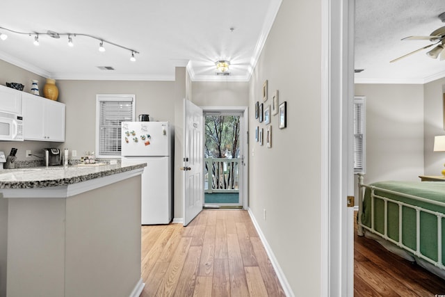 kitchen featuring white cabinetry, light wood-type flooring, light stone counters, crown molding, and white appliances