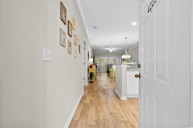 corridor with ornamental molding and light hardwood / wood-style flooring