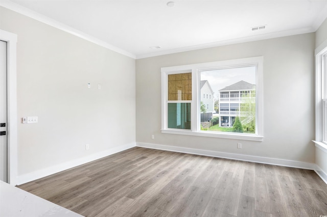 empty room with ornamental molding and light hardwood / wood-style floors