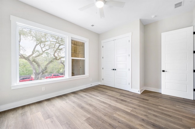 unfurnished bedroom with hardwood / wood-style flooring, ceiling fan, and a closet