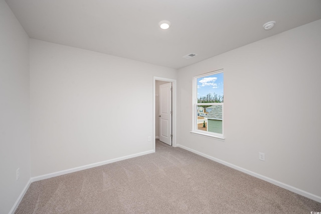 carpeted spare room featuring baseboards and visible vents