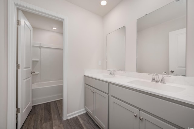 bathroom with double vanity, baseboards, a sink, and wood finished floors