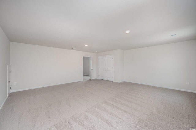 unfurnished room featuring recessed lighting, baseboards, light colored carpet, and visible vents