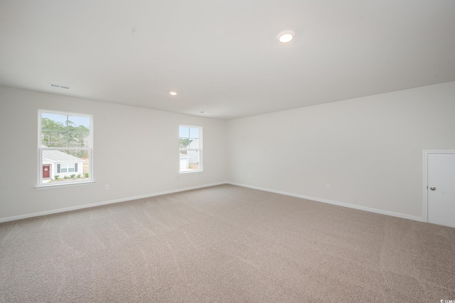 empty room featuring light colored carpet, baseboards, and plenty of natural light