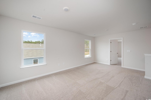 empty room with baseboards, visible vents, and light carpet