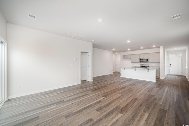 unfurnished living room with recessed lighting, baseboards, wood finished floors, and visible vents