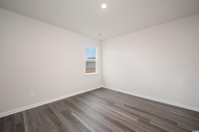 spare room with baseboards, visible vents, and dark wood-type flooring