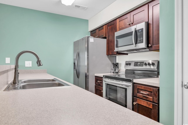 kitchen with stainless steel appliances, light countertops, a sink, and visible vents