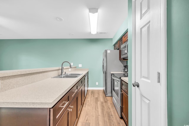 kitchen with visible vents, stainless steel appliances, light countertops, light wood-style floors, and a sink