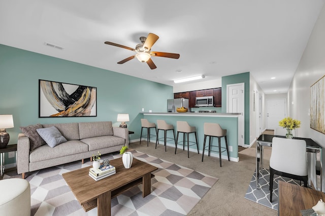 living area with visible vents, ceiling fan, light carpet, and baseboards