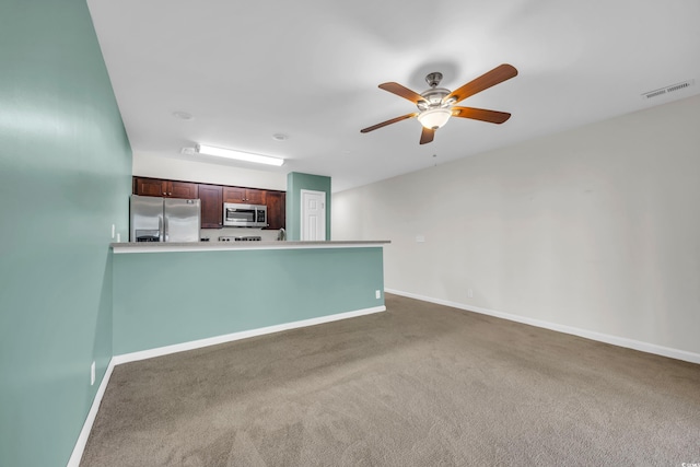 unfurnished living room featuring a ceiling fan, dark colored carpet, visible vents, and baseboards