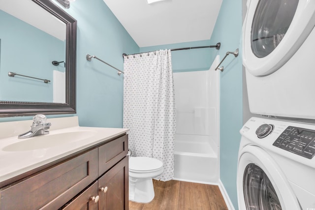 full bath with toilet, shower / tub combo with curtain, stacked washer / drying machine, wood finished floors, and vanity