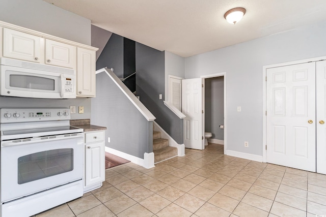 kitchen with white appliances, white cabinets, and light tile patterned flooring