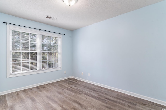 spare room with light hardwood / wood-style floors and a textured ceiling