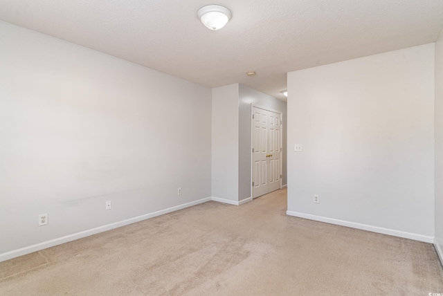 empty room with light colored carpet and a textured ceiling