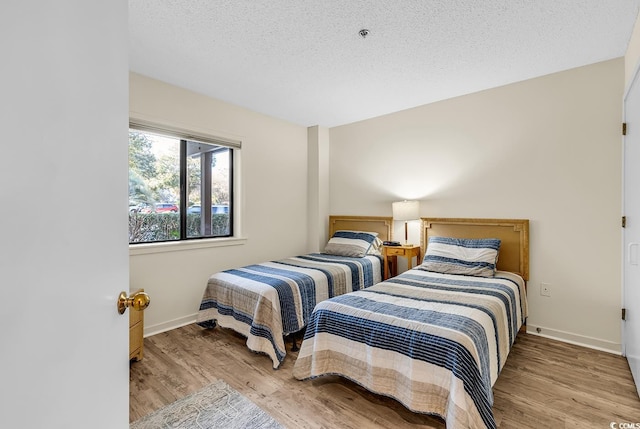 bedroom featuring a textured ceiling and light hardwood / wood-style flooring