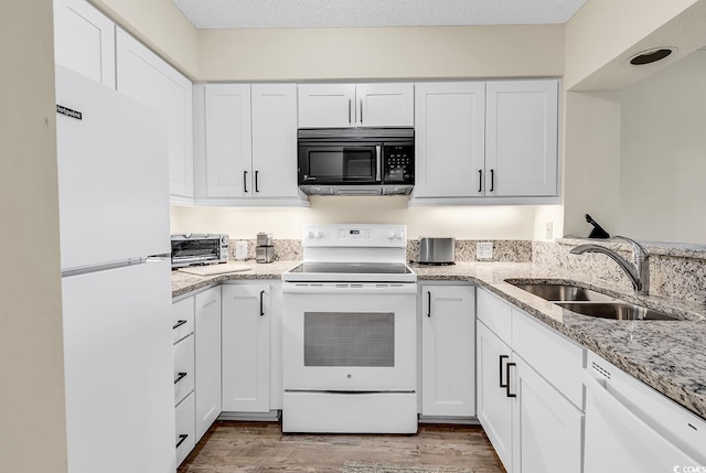 kitchen with sink, white cabinets, light stone countertops, white appliances, and light hardwood / wood-style flooring