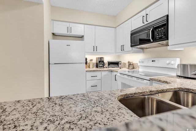 kitchen with white appliances, light stone countertops, and white cabinets