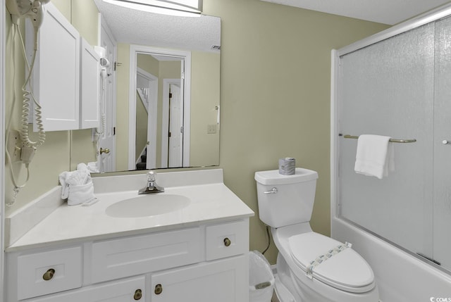 full bathroom with bath / shower combo with glass door, vanity, toilet, and a textured ceiling