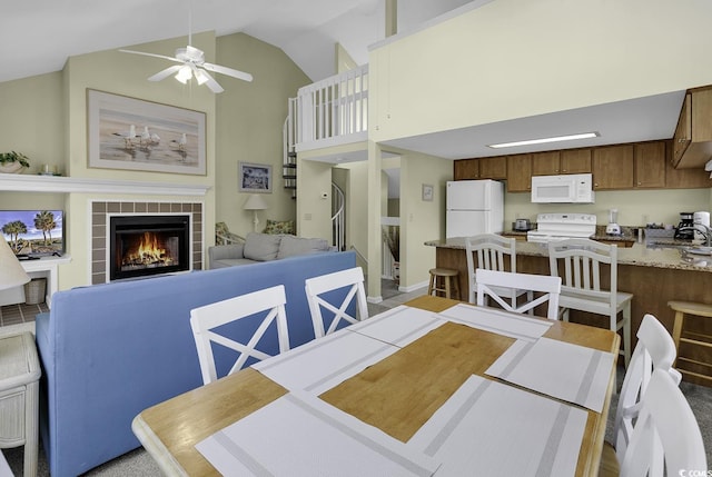 dining space with ceiling fan, high vaulted ceiling, sink, and a fireplace