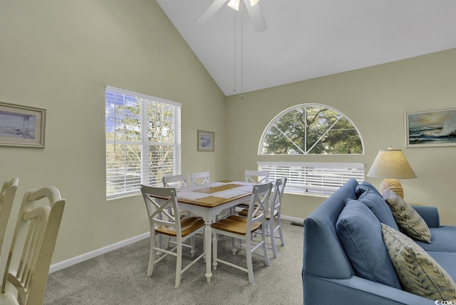 dining room with ceiling fan, light colored carpet, and high vaulted ceiling