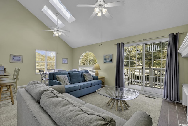 tiled living room with a skylight, high vaulted ceiling, and ceiling fan