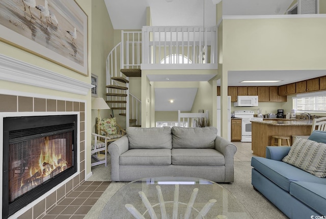 tiled living room with a high ceiling, crown molding, sink, and a fireplace