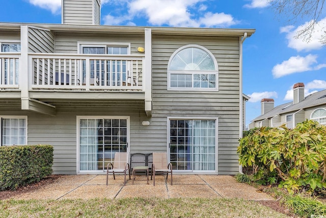 rear view of house featuring a patio and a balcony