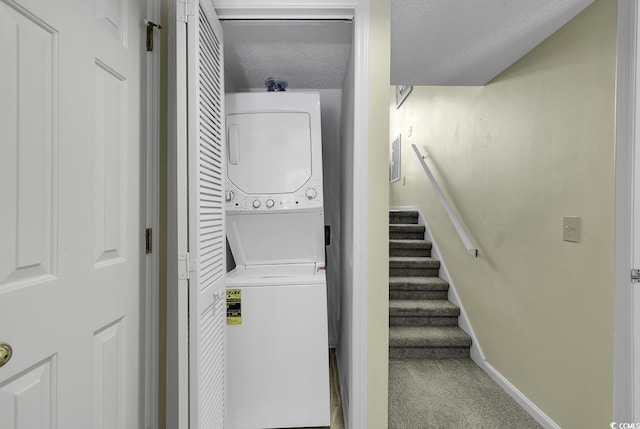 laundry room featuring stacked washer and clothes dryer, carpet floors, and a textured ceiling