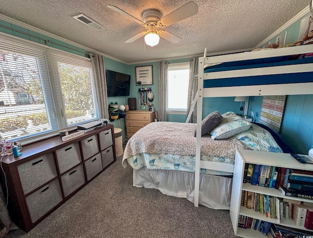 bedroom with ornamental molding, carpet flooring, ceiling fan, and a textured ceiling