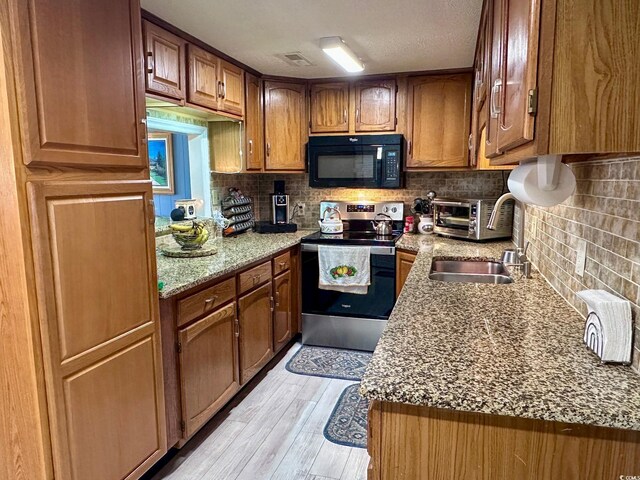 kitchen with sink, stainless steel electric range, tasteful backsplash, light stone countertops, and light hardwood / wood-style floors