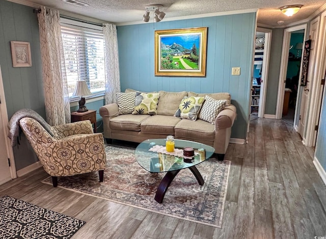 living room featuring wood-type flooring, ornamental molding, and a textured ceiling