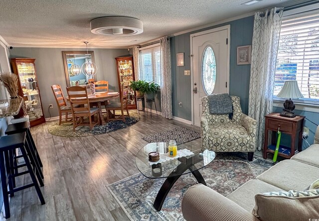 living room featuring hardwood / wood-style floors, a notable chandelier, ornamental molding, and a textured ceiling