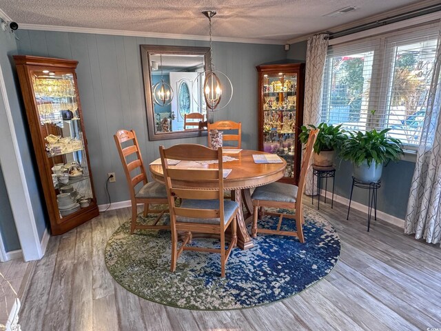 dining space featuring hardwood / wood-style flooring, crown molding, a chandelier, and a textured ceiling