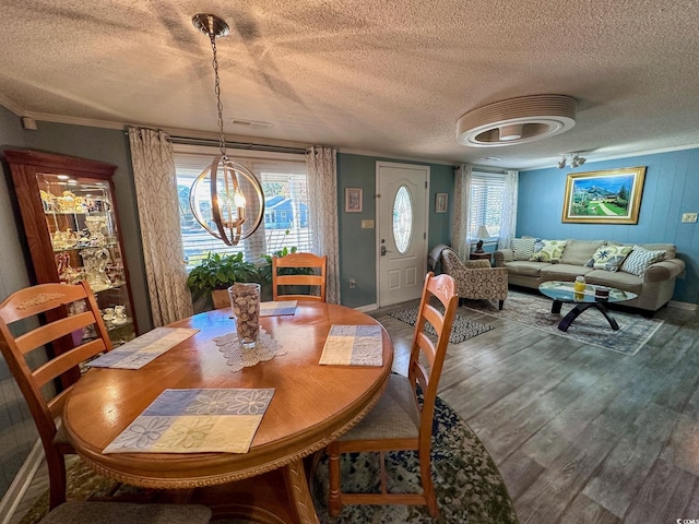 dining space featuring crown molding, a healthy amount of sunlight, wood-type flooring, and a notable chandelier