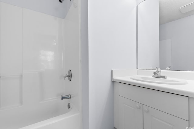 bathroom with vanity, a textured ceiling, and washtub / shower combination