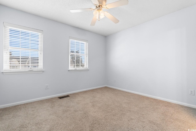 unfurnished room with ceiling fan, a healthy amount of sunlight, carpet, and a textured ceiling