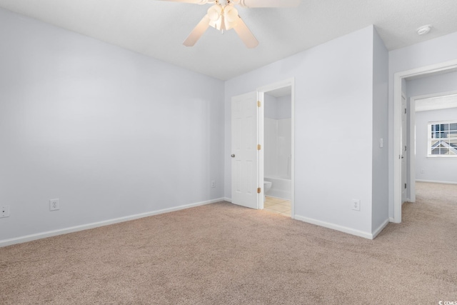 unfurnished bedroom with ceiling fan, light colored carpet, and ensuite bath