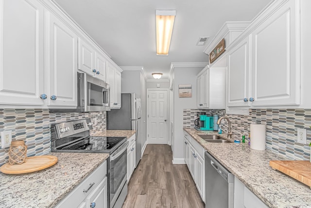 kitchen featuring white cabinetry, appliances with stainless steel finishes, sink, and crown molding