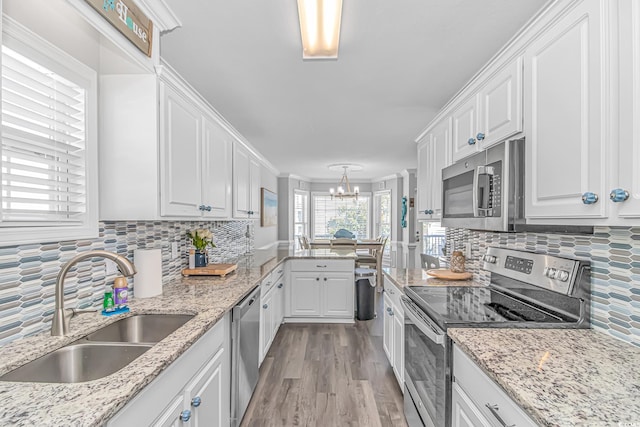 kitchen with tasteful backsplash, sink, white cabinets, stainless steel appliances, and light hardwood / wood-style flooring