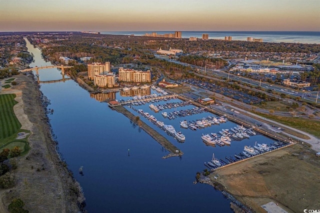 aerial view at dusk featuring a water view and a beach view