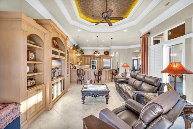 living room with crown molding, ceiling fan, a tray ceiling, and built in features