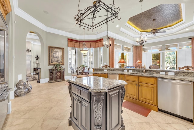 kitchen with a kitchen island, decorative light fixtures, stainless steel dishwasher, a raised ceiling, and light stone countertops