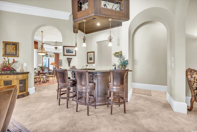 bar with pendant lighting, crown molding, and a high ceiling