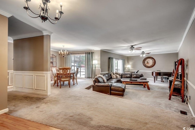 living room featuring ornamental molding, ceiling fan with notable chandelier, and light carpet