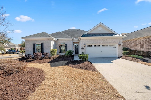 view of front of property with metal roof, an attached garage, brick siding, concrete driveway, and a standing seam roof