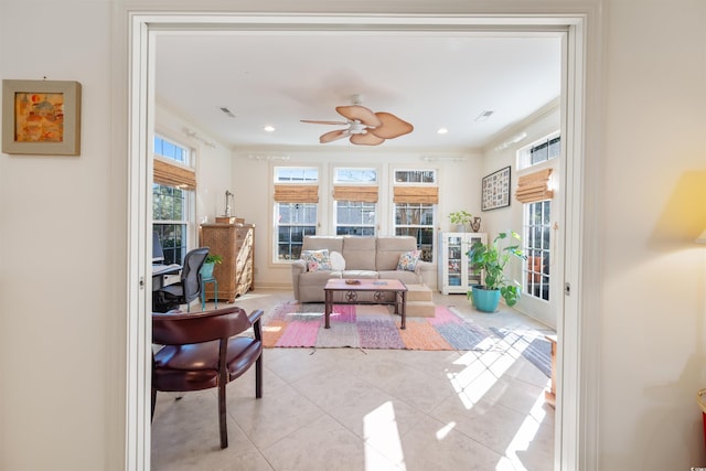 living area with a wealth of natural light, tile patterned floors, crown molding, and ceiling fan