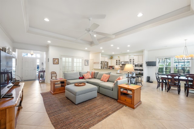 living area with a tray ceiling, recessed lighting, light tile patterned floors, and ceiling fan with notable chandelier