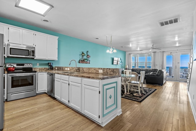 2022 N Waccamaw Dr, Garden City Beach, SC 29576 - kitchen featuring stainless steel appliances, a peninsula, a sink, white cabinetry, and light wood-type flooring